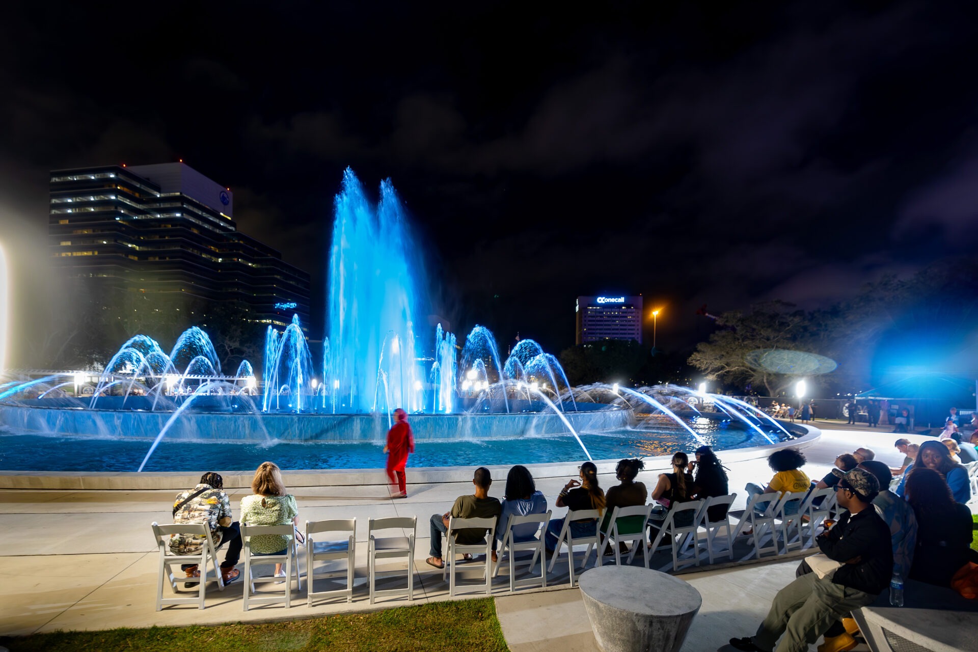 A fashion show in front of a large fountain.