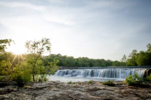 Courtesy Visit Joplin A picture of a waterfall with the sun rising in the background.