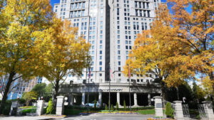 A front view of the Grand Hyatt Atlanta in Buckhead with fall-colored trees at both sides .