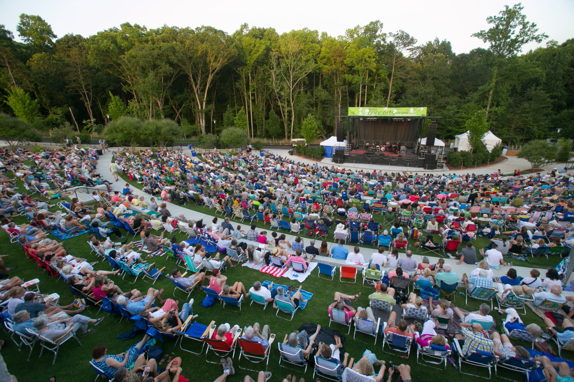 A photo of a grassy amphitheater space amongst a backdrop of trees.