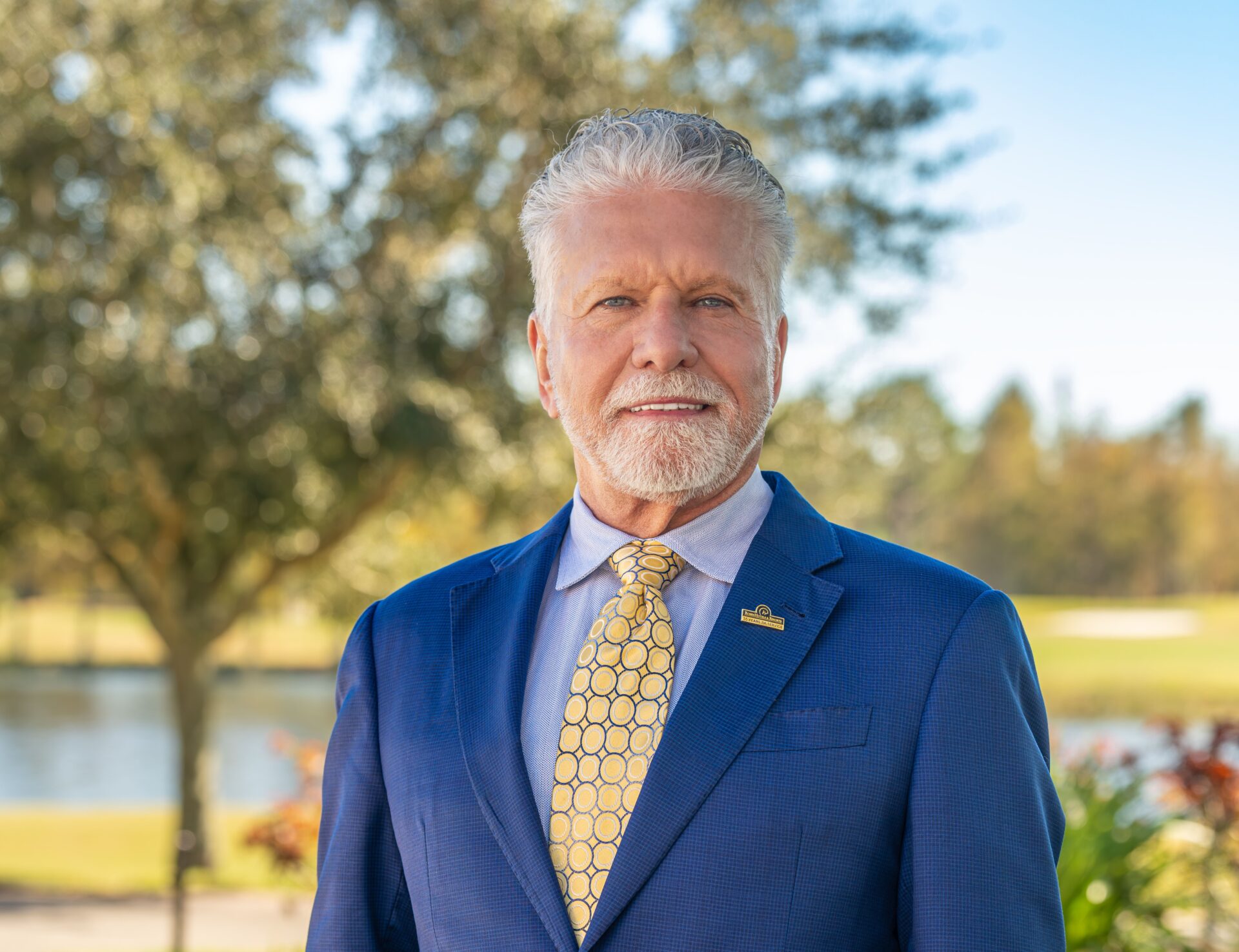 A headshot of Frank Santos in a blue suit.
