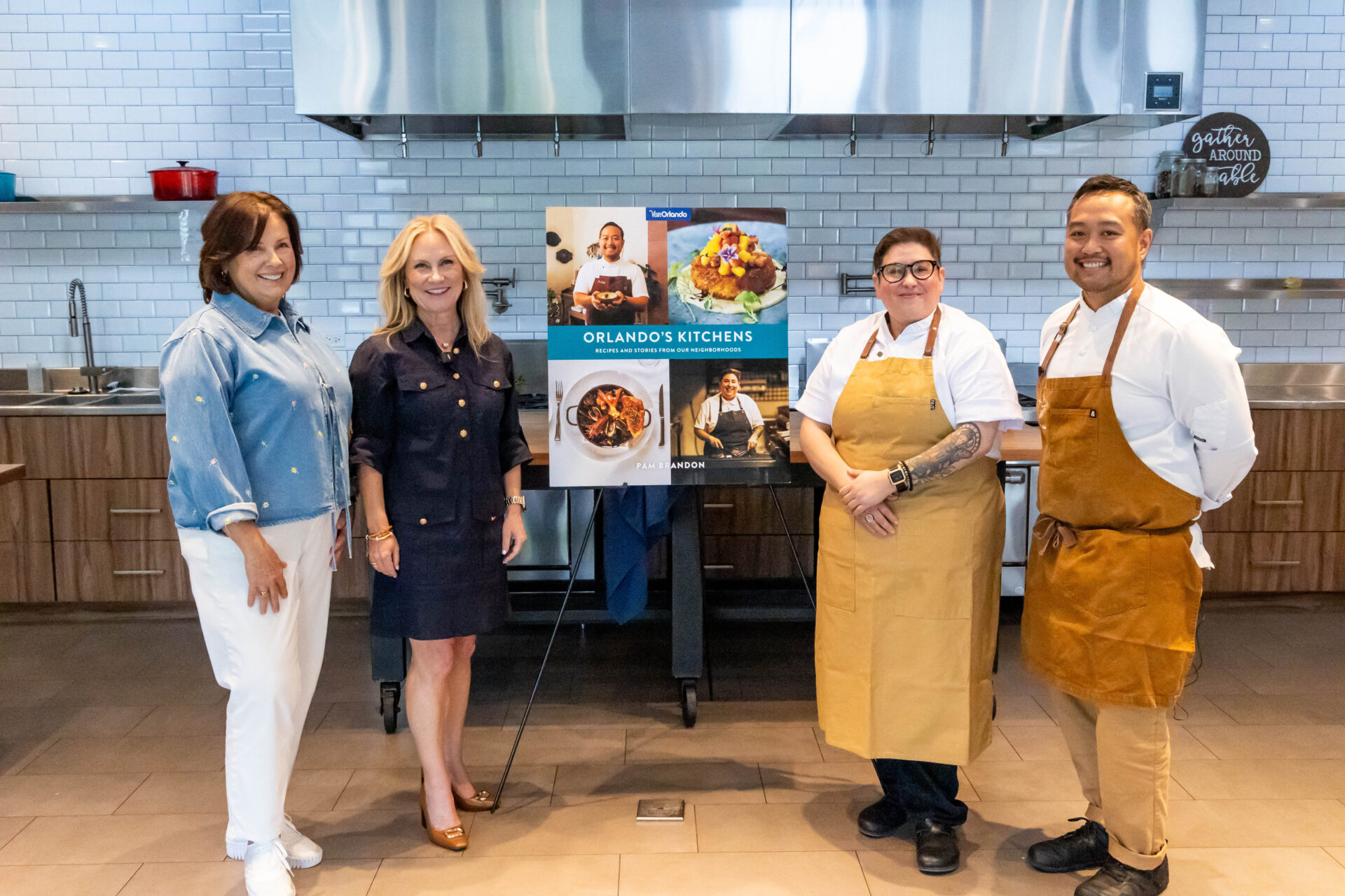 Four people posing with a poster for the cookbook, Orlando’s Kitchens: Recipes and Stories From Our Neighborhoods.