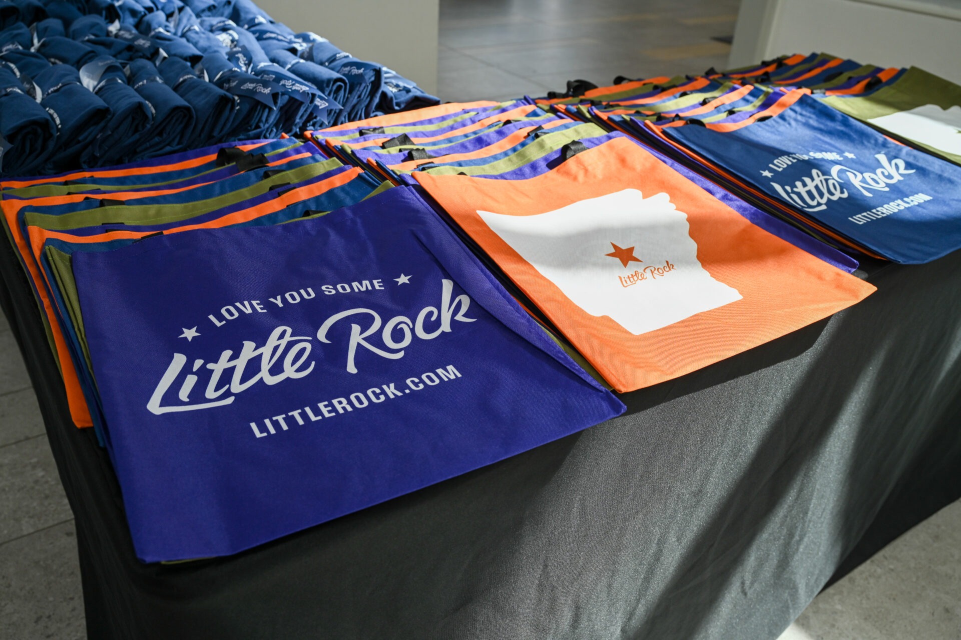 A spread of tote bags on a table that say ‘Love You Some Little Rock.’
