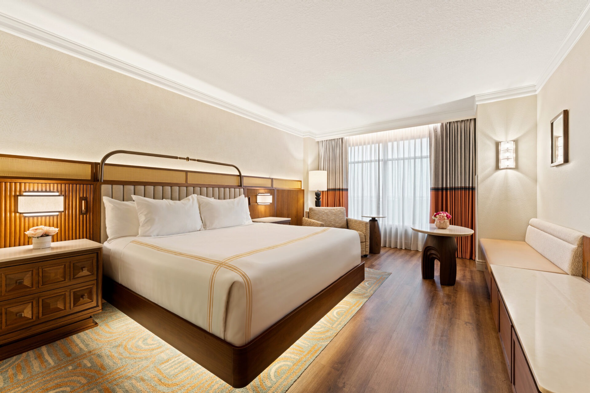 A hotel room with a king bed. The room has wood accents.
