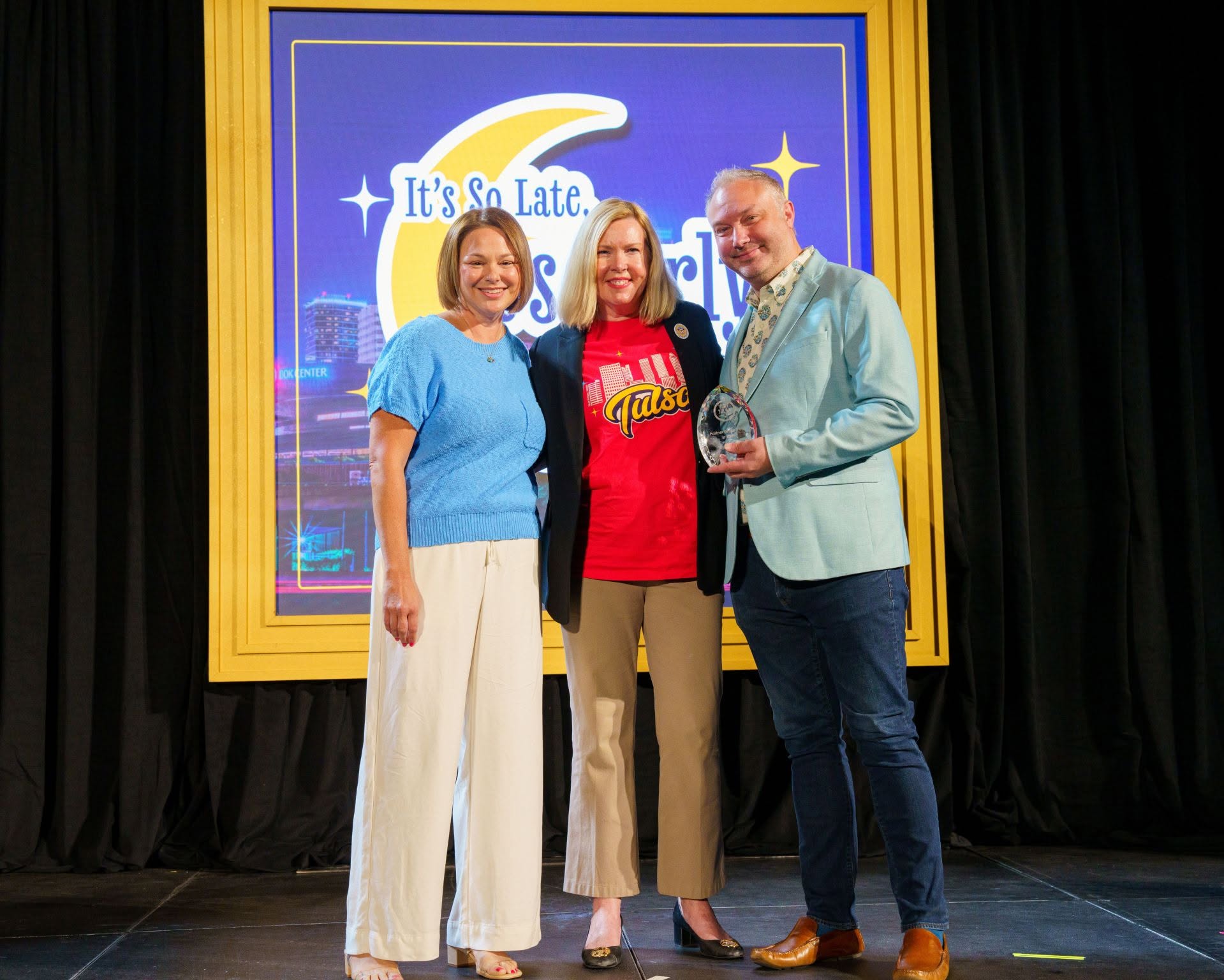 From left, Ashley Armstrong, president of factor 110; Renee McKenney, president of Tulsa Regional Tourism; and Brian Ferrell, factor 110 founder and CEO, pose together, with Ferrell holding an award.